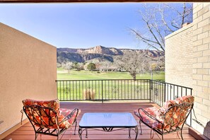 A balcony with two chairs and a table, overlooking a scenic landscape with mountains and a golf course. - Grand Junction Golf Course Condo w/ Balconies (Grand Junction)