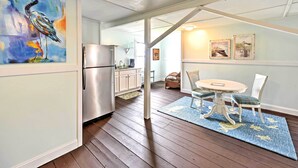 A modern kitchen with a stainless steel refrigerator, wooden cabinets, and a dining area with a round table and chairs. - Historic Swansboro Studio w/ Intracoastal View! (Swansboro)