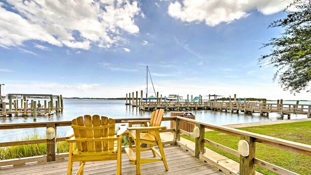 A wooden deck with two Adirondack chairs overlooking a water body with docks and boats. - Historic Swansboro Studio w/ Intracoastal View! (Swansboro)