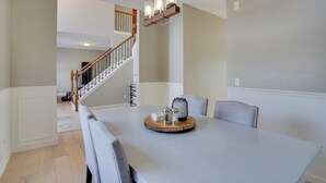 A dining area with a large table, chairs, and a chandelier. A staircase is visible in the background. - Cozy Eden Prairie Home < 21 Mi to Twin Cities (Eden Prairie)