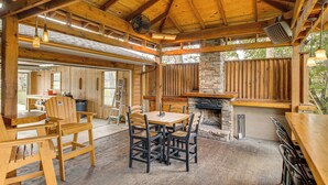 A rustic wooden dining area with a stone fireplace, wooden tables, and chairs. - Troutfest: Anglers Retreat on White River w/ Deck (Cotter)