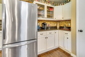 A kitchen with white cabinets, a stainless steel refrigerator, and a coffee maker on the counter. - Troutfest: Anglers Retreat on White River w/ Deck (Cotter)