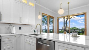 A modern kitchen with white cabinetry, a stainless steel dishwasher, and a large window offering a view of the outdoors. - Hiking On-site: Mtn-view Burnsville Condo! (Burnsville)