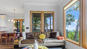 A modern living room with a large window, a sofa, a coffee table, and a dining area. - Hiking On-site: Mtn-view Burnsville Condo! (Burnsville)
