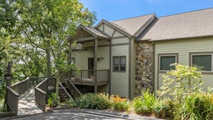 A two-story lodge with a stone facade, a covered porch, and a wooden staircase leading to the upper level. - Hiking On-site: Mtn-view Burnsville Condo! (Burnsville)