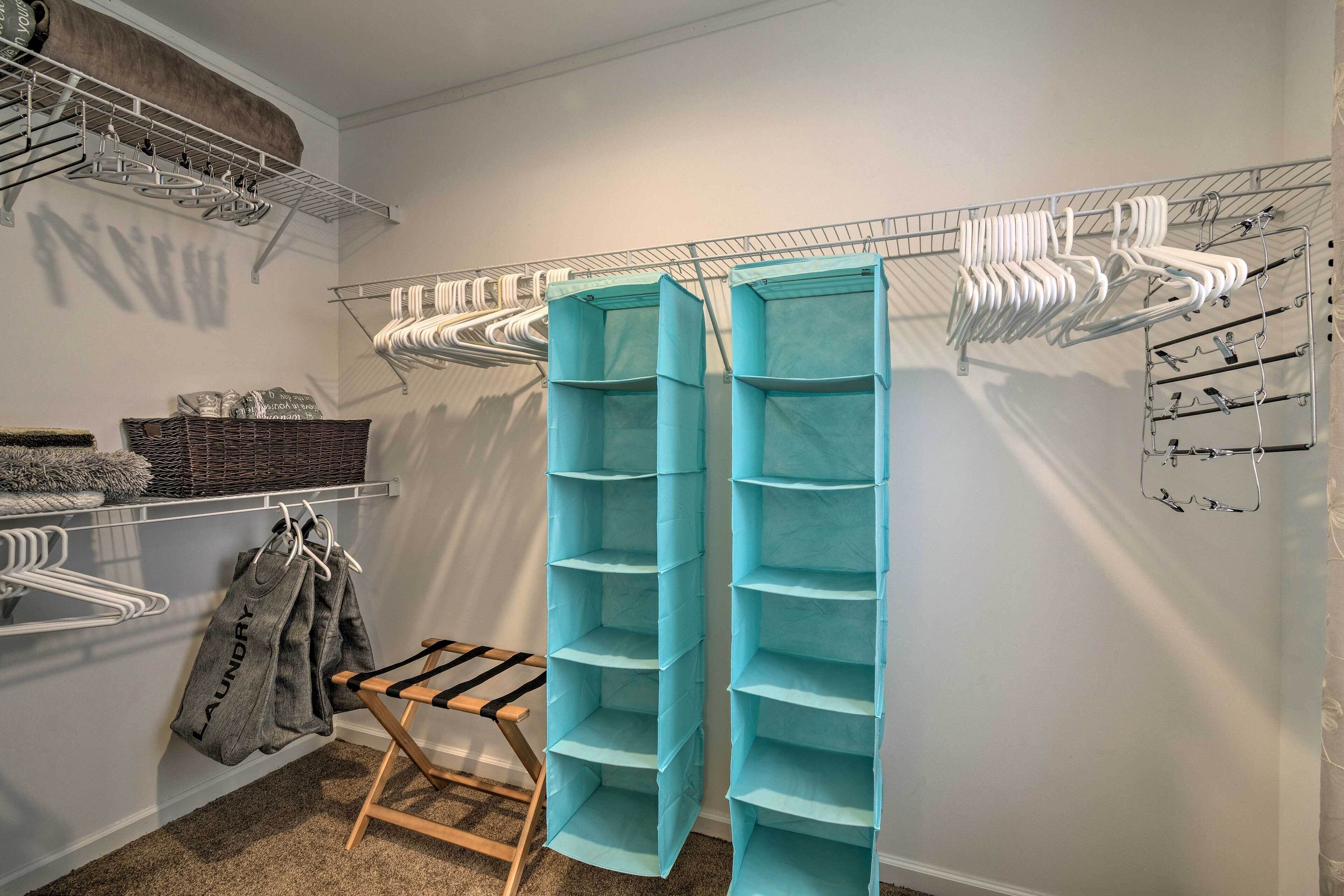 A storage closet with shelves, hanging racks, and a folding chair.