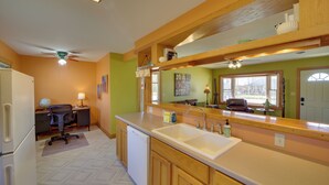 Una cocina con armarios de madera, un lavavajillas blanco y un espejo grande sobre el fregadero.