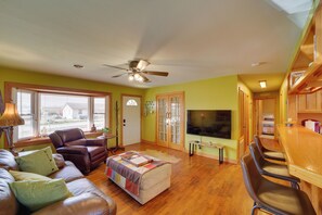 A living room with a leather couch, a wooden coffee table, a ceiling fan, and a TV.