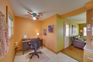 A room with a desk, chair, globe, lamp, and a couch.