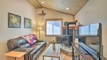 A cozy living room with a leather couch, a wooden coffee table, a fireplace, and framed artwork on the walls.