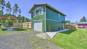 A two-story house with a green exterior, a white garage door, and a covered patio area.