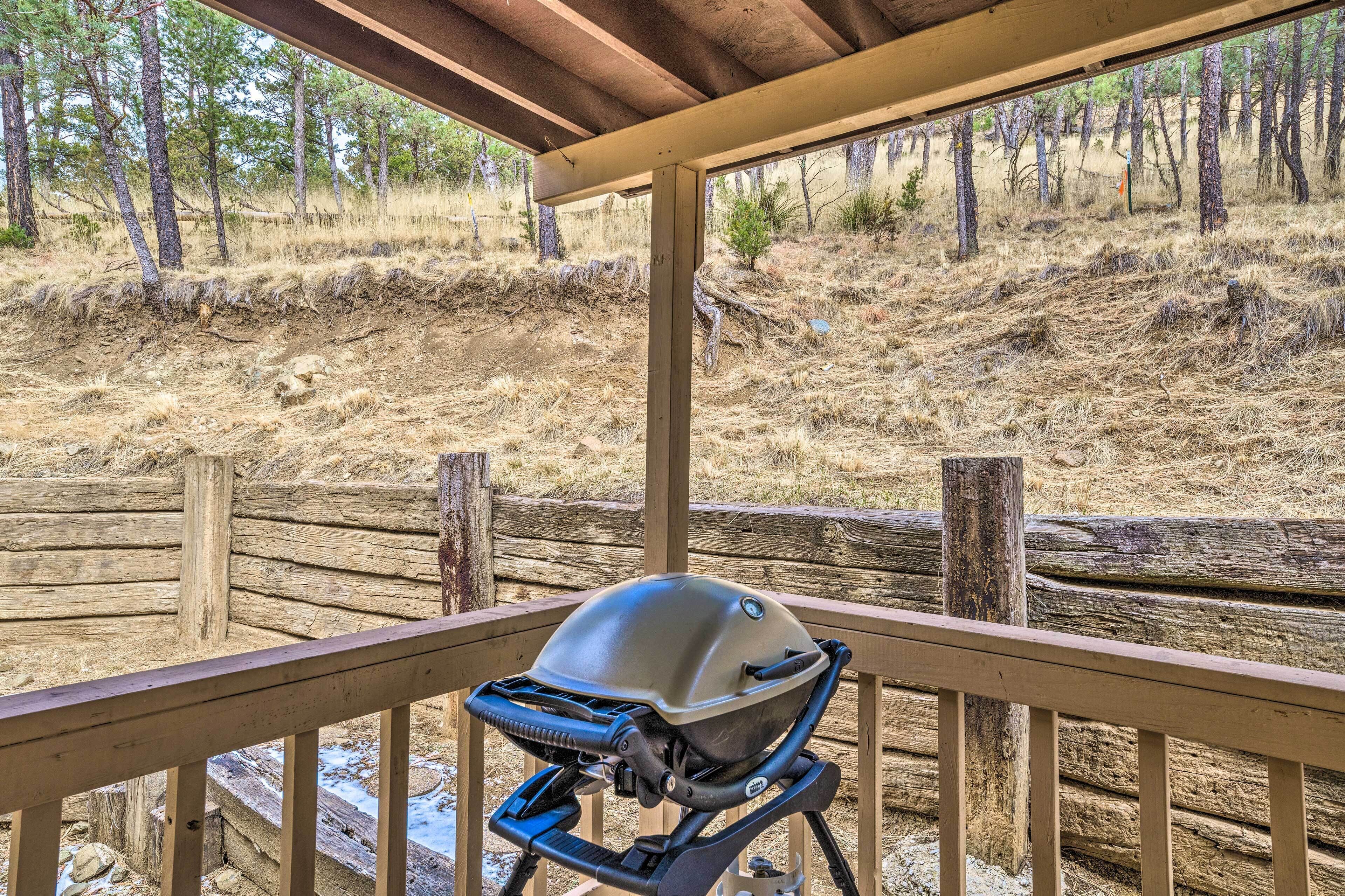 A covered outdoor area with a grill and a wooden fence.