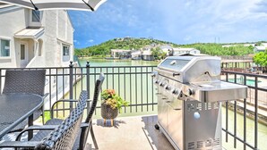 A balcony with a grill, wicker chairs, and a view of a lake and buildings. - Waterfront Horseshoe Bay Retreat w/ Game Room! (Horseshoe Bay)