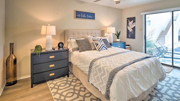 A bedroom with a bed, nightstands, a ceiling fan, a wall-mounted sign, and a view of a staircase. - Waterfront Horseshoe Bay Retreat w/ Game Room! (Horseshoe Bay)