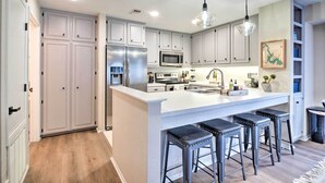A modern kitchen with white cabinets, stainless steel appliances, and a central island with bar stools. - Waterfront Horseshoe Bay Retreat w/ Game Room! (Horseshoe Bay)