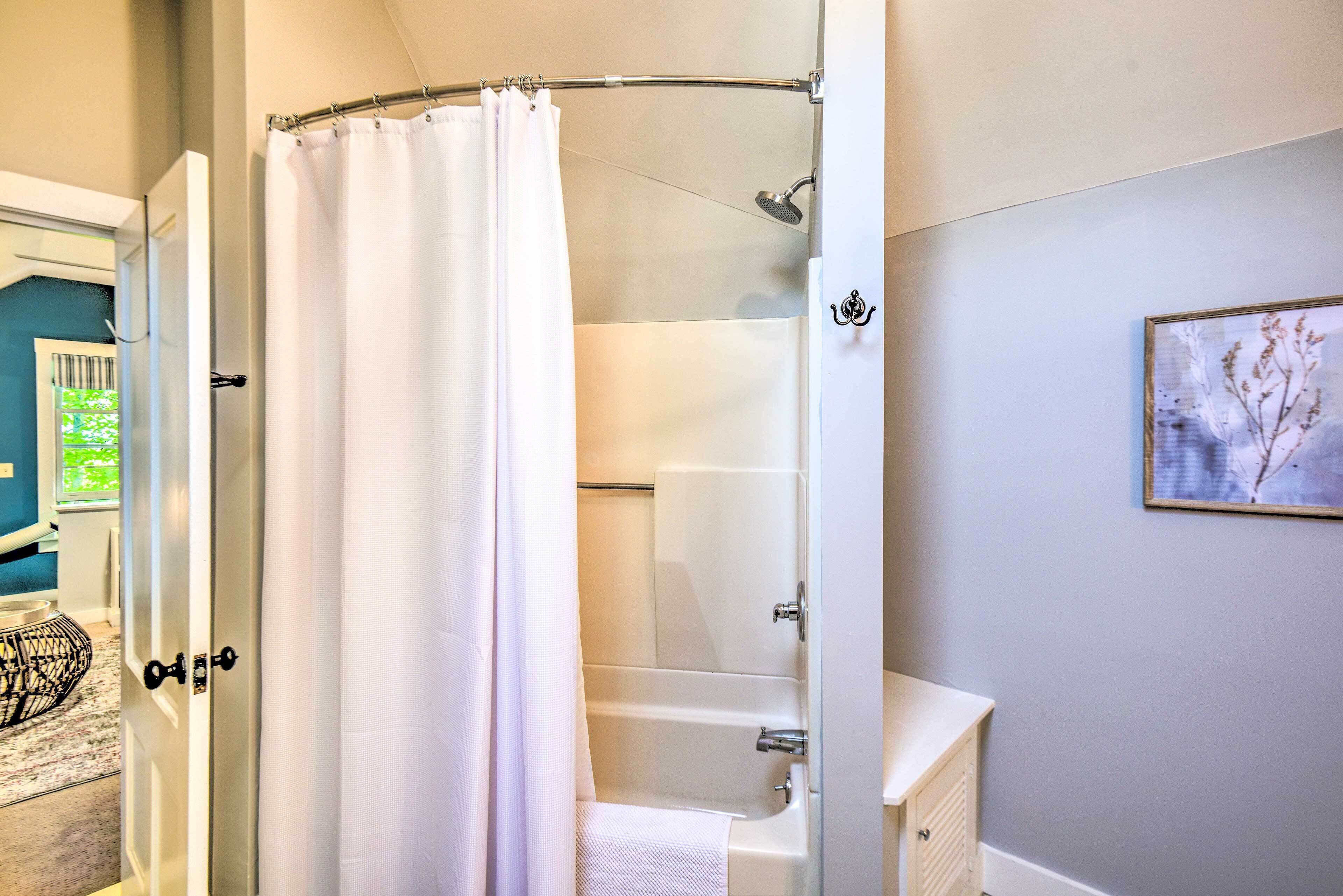 A bathroom with a shower curtain, a bathtub, a toilet, and a sink.