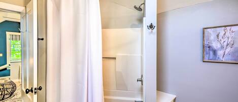 A bathroom with a shower curtain, a bathtub, a toilet, and a sink.