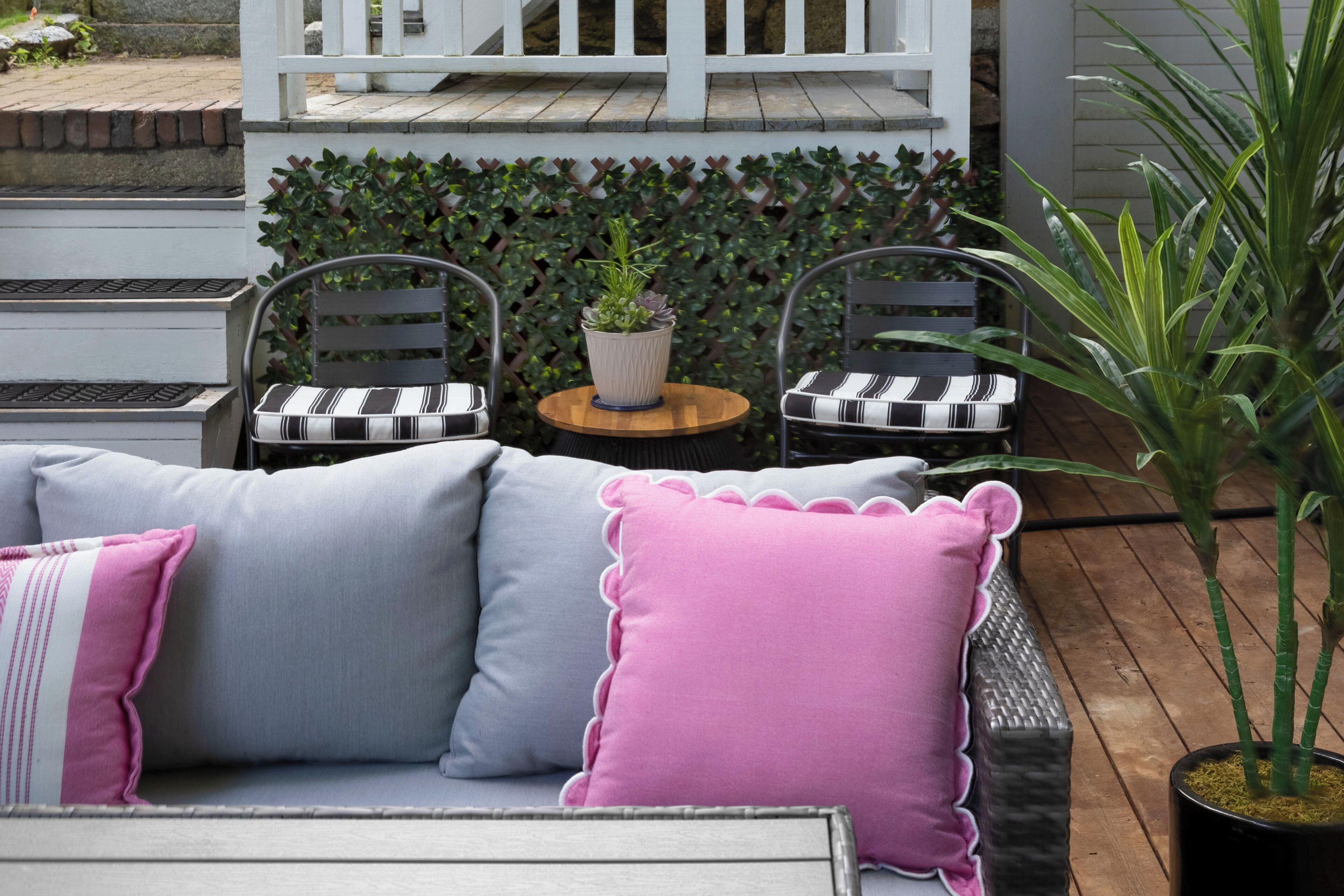 A patio with a gray sofa, two chairs, a small round table, and a potted plant.
