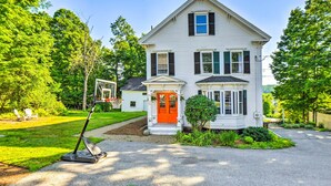 Ein zweistöckiges Haus mit Veranda, Basketballkorb und gepflegtem Rasen.