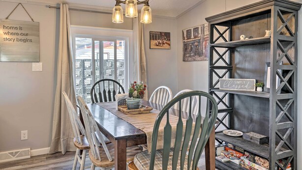 A dining area with a wooden table, chairs, a chandelier, and a bookshelf. - Pet-friendly Home ~ 3 Mi to Downtown Pueblo! (Pueblo)
