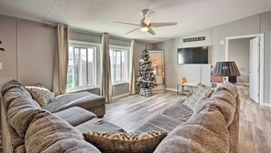 A living room with a large sectional sofa, a ceiling fan, a Christmas tree, and a sign reading "FARMHOUSE". - Pet-friendly Home ~ 3 Mi to Downtown Pueblo! (Pueblo)