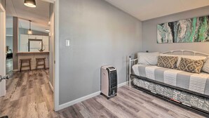 A bedroom with a bed, a heater, and a kitchen in the background. - Pet-friendly Home ~ 3 Mi to Downtown Pueblo! (Pueblo)