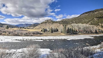 A river with ice, a mountain, and a house surrounded by trees.