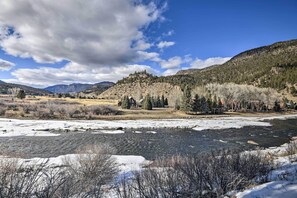 A river with ice, a mountain, and a house surrounded by trees.