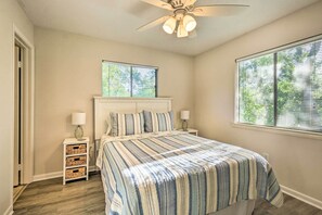 Ein Schlafzimmer mit einem Bett, zwei Nachttischen, einem Deckenventilator und Fenstern mit Jalousien.