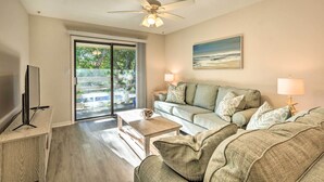 A living room with a ceiling fan, a television, a sofa, a coffee table, and a painting on the wall.