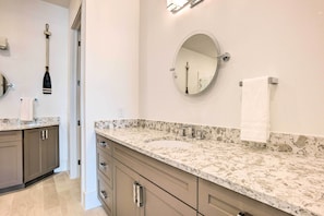 A bathroom with a marble countertop, a round mirror, and a towel rack. - Lakeside Montgomery Condo Near Boat Rental! (Montgomery)