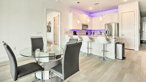 A modern kitchen with white cabinets, stainless steel appliances, and a glass dining table with black chairs. - Lakeside Montgomery Condo Near Boat Rental! (Montgomery)