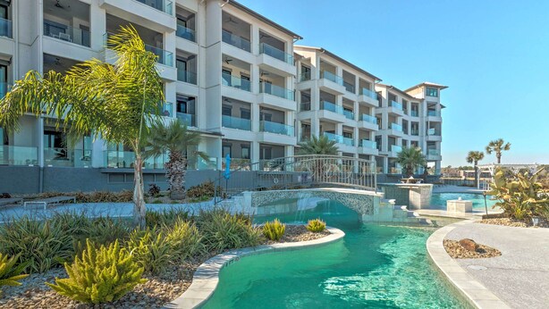 A modern hotel with a swimming pool, surrounded by palm trees and a clear blue sky. - Lakeside Montgomery Condo Near Boat Rental! (Montgomery)