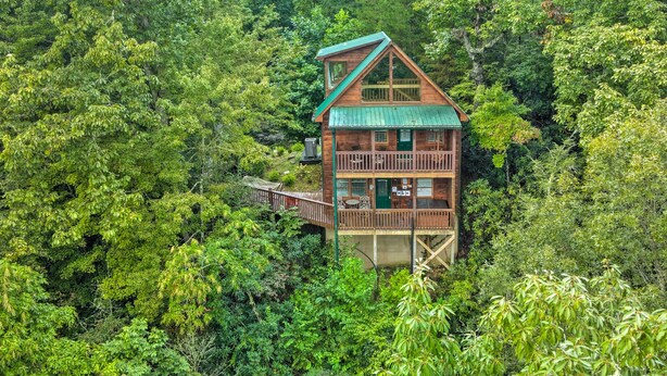 Eine Hütte mit Balkon und Terrasse, umgeben von dichtem Wald.