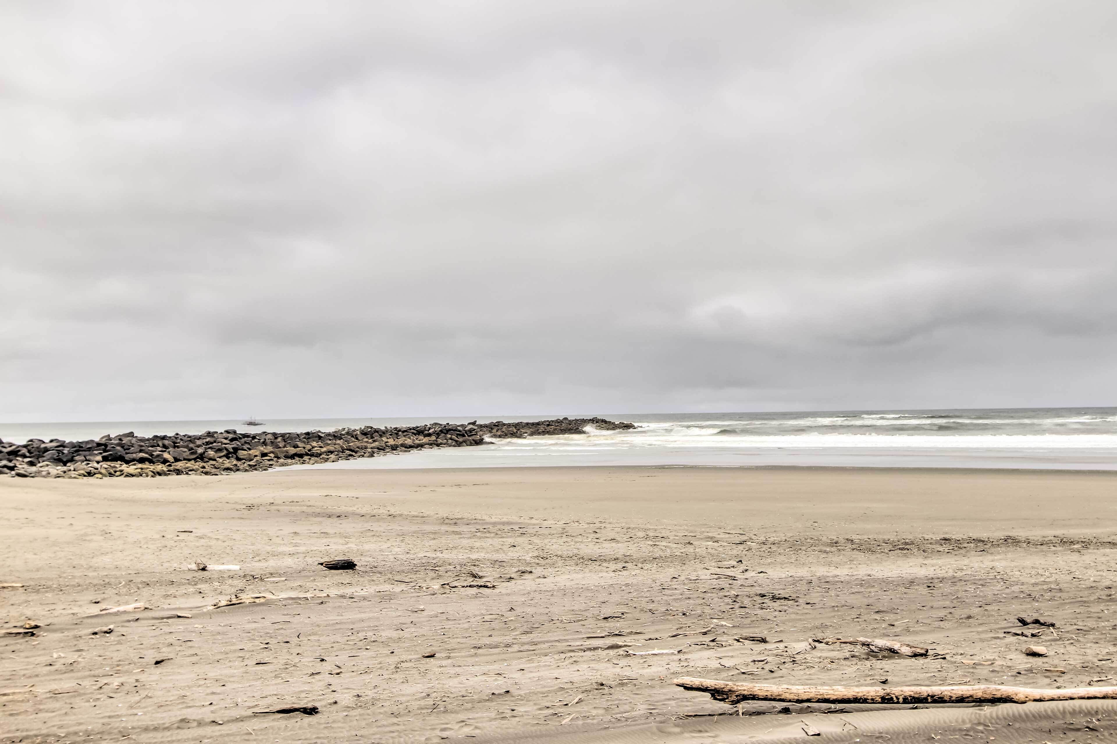 A beach with a rocky breakwater and calm waves.