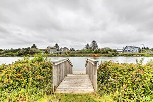 Un muelle de madera que lleva a un lago tranquilo con casas al fondo.