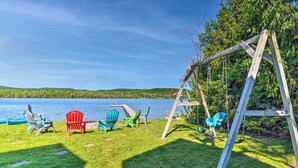 A wooden swing set and Adirondack chairs by a lake. - Lakefront Bellaire Getaway w/ Kayaks, Dock & Grill (Bellaire)