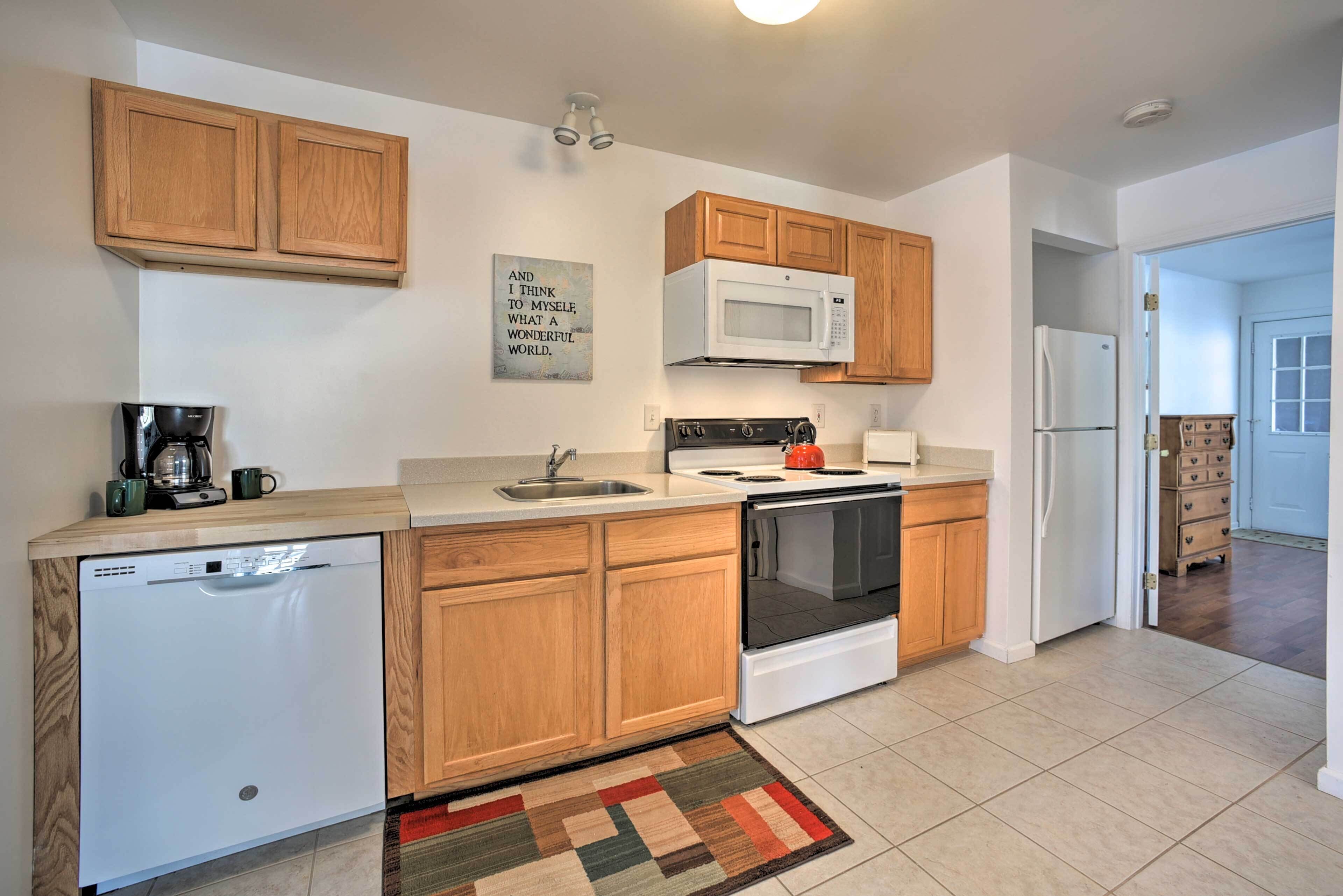 A modern kitchen with wooden cabinets, a built-in microwave, a stove, and a dishwasher.