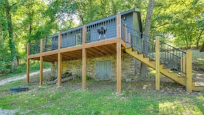 Eine Holzterrasse mit einer Treppe, die zu einem Steinhaus führt.