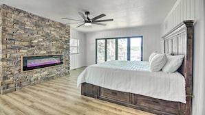 Ein Schlafzimmer mit Steinsandsteinwand, einem Bett mit Holz-Kopfstück, einem Deckenventilator und einem Fenster mit Blick.