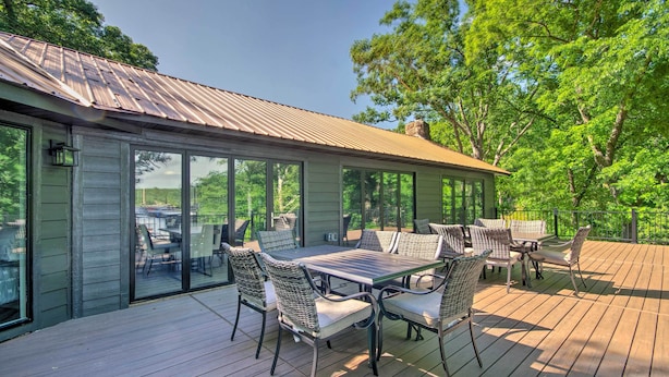 Eine Terrasse mit Esstisch und Stühlen, großen Fenstern und einem Metalldach.