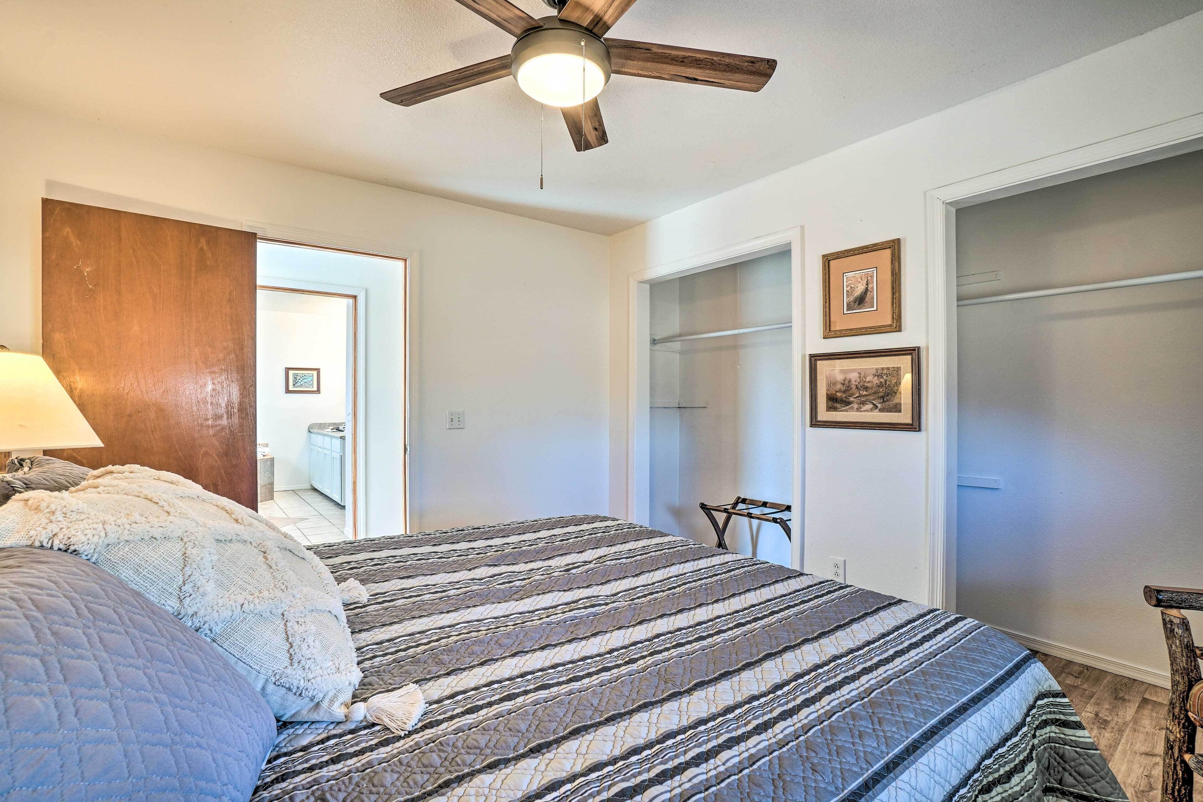 A bedroom with a bed, a ceiling fan, a wardrobe, and a chair.