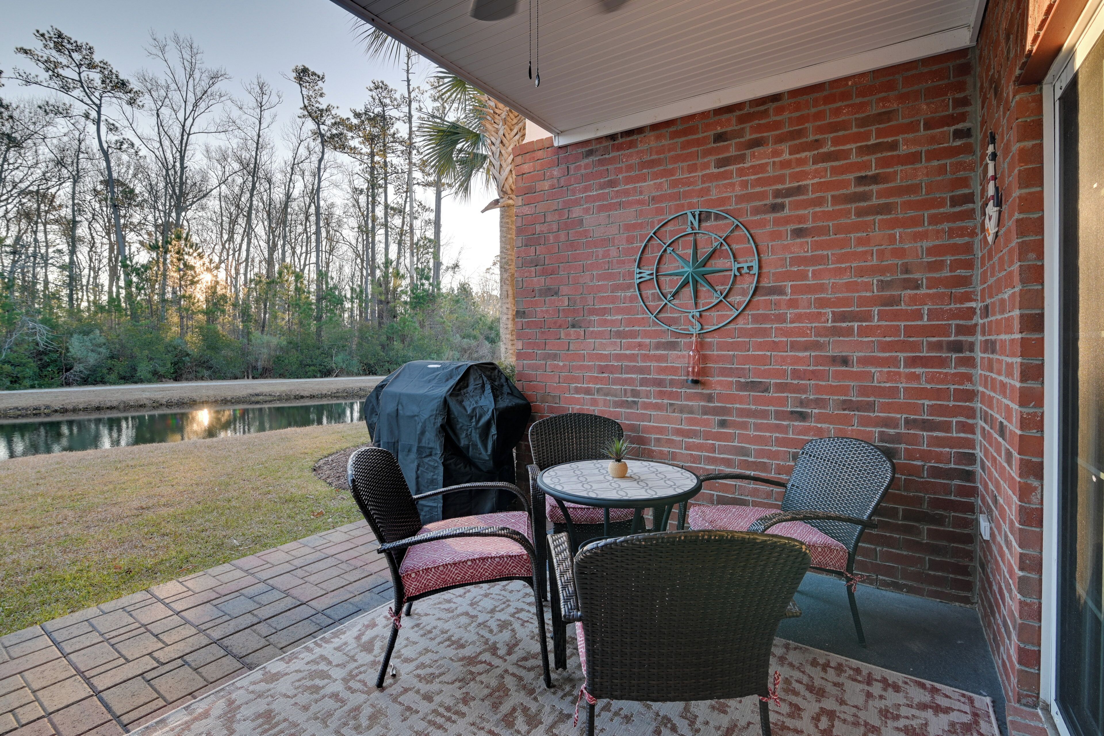 A patio with wicker chairs and a table, a brick wall, and a compass decoration.