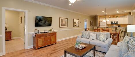 A spacious living room with a large television, a wooden cabinet, a sofa, and a coffee table.