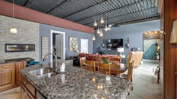 A spacious kitchen with granite countertops, a large island, and modern lighting fixtures.