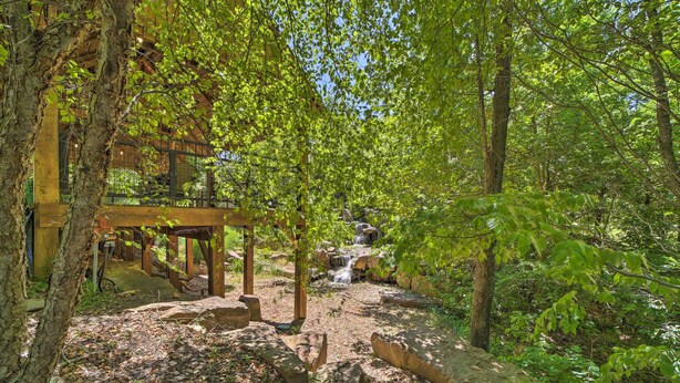 Un belvédère en bois, avec un sentier de pierres menant à une petite cascade.