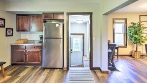 A kitchen with wooden cabinets, a stainless steel refrigerator, a dining area with a table and chairs, and a potted plant. - Appleton Abode Near Lake Winnebago & Downtown (Appleton)