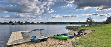Un entorno frente al lago con playa de arena, rampa para embarcaciones, kayaks y una fila de sillas.