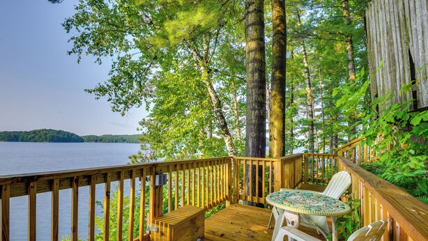 Una terraza de madera con una mesa y sillas que da a un lago.