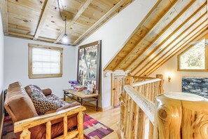 A cozy loft-style room with a wooden ceiling, a sofa, a table with various items, and a large window. - Secluded White River Haven! 4 Mi to Devil's Knob (Melbourne)